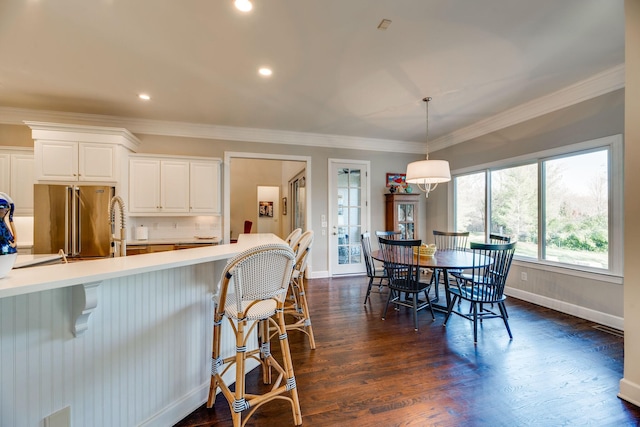 kitchen with dark hardwood / wood-style floors, white cabinetry, high end fridge, hanging light fixtures, and ornamental molding