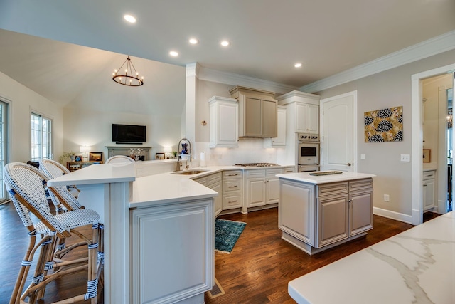 kitchen featuring sink, backsplash, kitchen peninsula, a notable chandelier, and a breakfast bar area