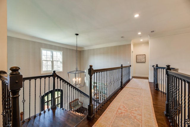 hallway featuring crown molding, wood-type flooring, and a notable chandelier