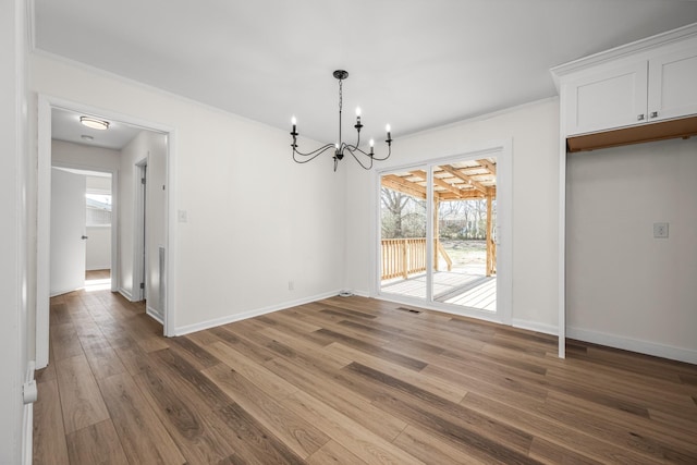 unfurnished dining area featuring dark hardwood / wood-style flooring, an inviting chandelier, and ornamental molding