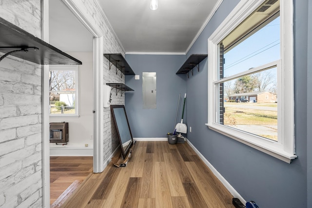 laundry room with brick wall, heating unit, ornamental molding, wood-type flooring, and electric panel