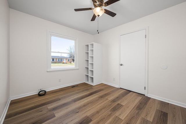 unfurnished bedroom with ceiling fan and dark hardwood / wood-style floors