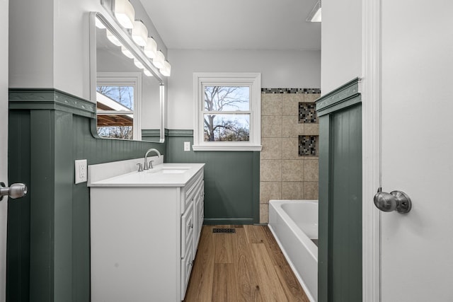 bathroom featuring hardwood / wood-style flooring, a wealth of natural light, vanity, and a bathing tub