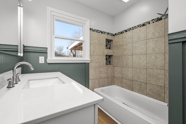 bathroom with hardwood / wood-style floors, tiled shower / bath combo, and vanity