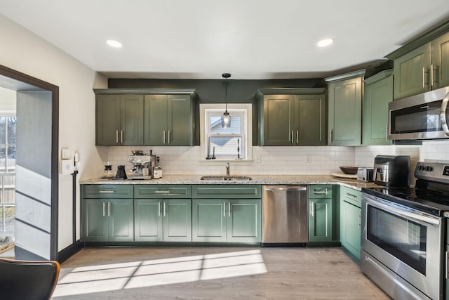 kitchen featuring decorative light fixtures, sink, green cabinets, and stainless steel appliances