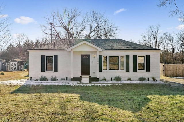 view of front of house with a front lawn and a storage shed