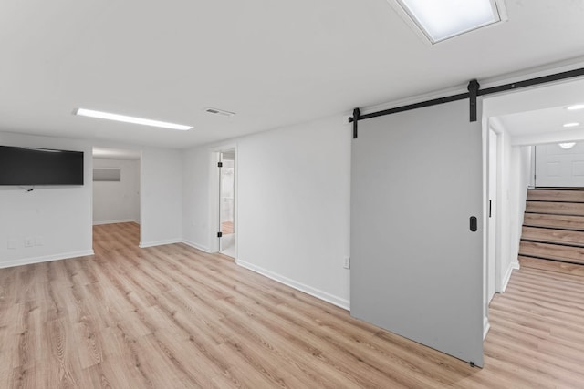 basement featuring a barn door and light hardwood / wood-style floors