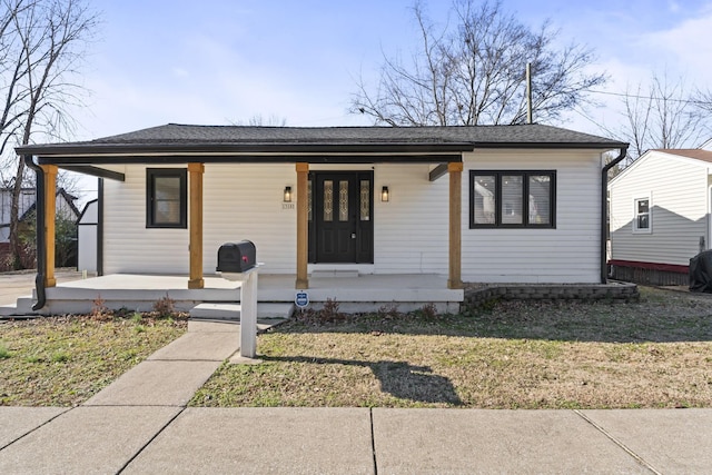 bungalow-style home featuring covered porch, roof with shingles, and a front lawn