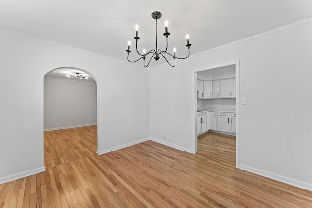 unfurnished dining area with crown molding, a chandelier, and light hardwood / wood-style floors