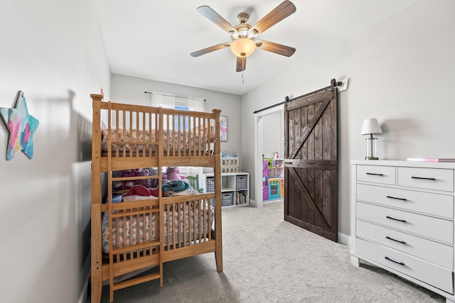 bedroom featuring ceiling fan, a barn door, and dark carpet