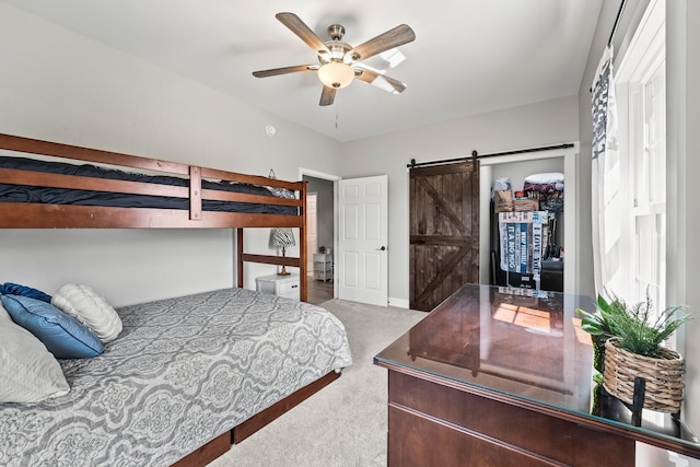 carpeted bedroom featuring ceiling fan, multiple windows, and a barn door