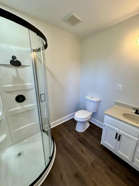 bathroom with toilet, vanity, a shower with door, and hardwood / wood-style flooring