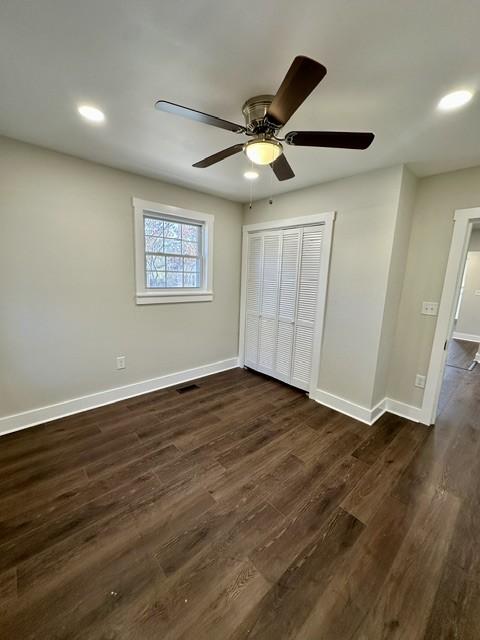 unfurnished bedroom featuring ceiling fan, dark hardwood / wood-style flooring, and a closet