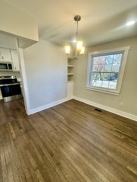 unfurnished dining area with an inviting chandelier and dark hardwood / wood-style floors