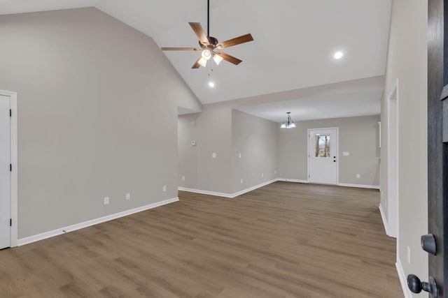 unfurnished living room with ceiling fan with notable chandelier, hardwood / wood-style flooring, and high vaulted ceiling