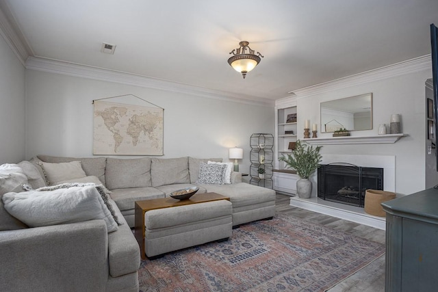 living room with built in shelves, dark wood-type flooring, and crown molding