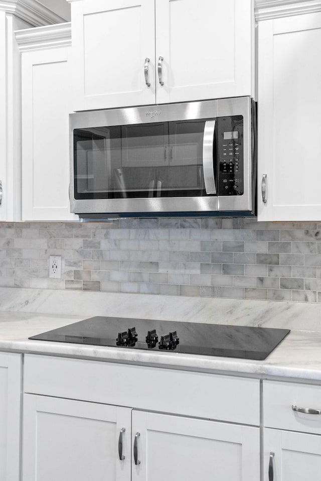 kitchen with black electric cooktop, white cabinets, and tasteful backsplash