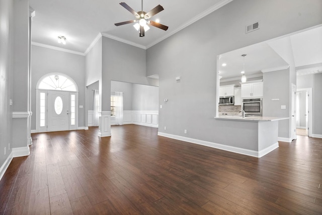 unfurnished living room with high vaulted ceiling, dark hardwood / wood-style floors, crown molding, and ceiling fan