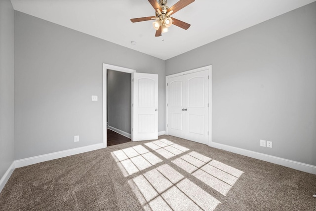 unfurnished bedroom with ceiling fan, a closet, and dark colored carpet