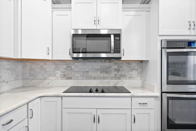 kitchen with tasteful backsplash, white cabinets, light stone countertops, and appliances with stainless steel finishes