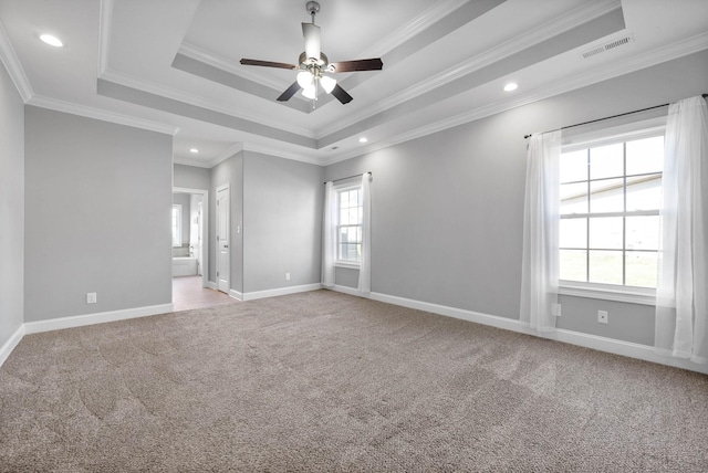 carpeted empty room with ceiling fan, crown molding, and a tray ceiling