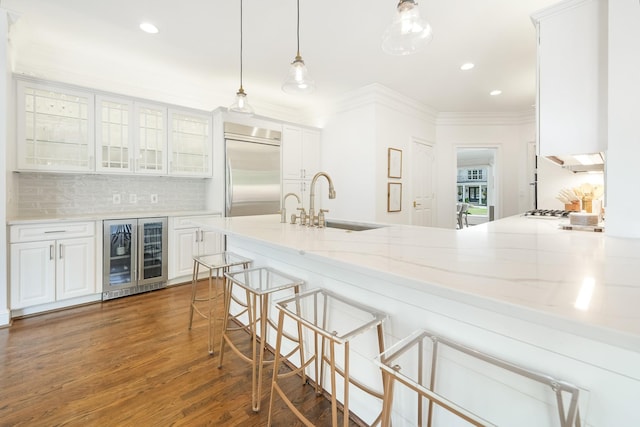 kitchen with beverage cooler, decorative light fixtures, white cabinetry, stainless steel built in fridge, and decorative backsplash