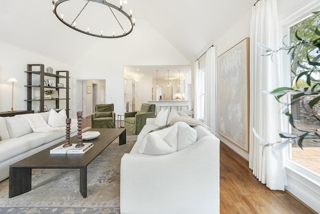 living room featuring high vaulted ceiling, a chandelier, and hardwood / wood-style floors