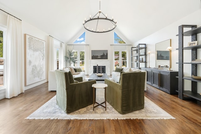 living room featuring high vaulted ceiling, an inviting chandelier, and light hardwood / wood-style floors