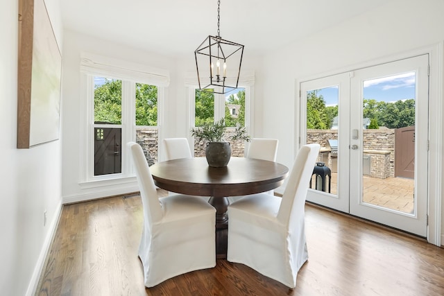 unfurnished dining area featuring wood-type flooring, an inviting chandelier, french doors, and a healthy amount of sunlight