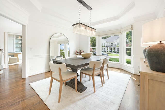 dining space featuring hardwood / wood-style floors, a tray ceiling, crown molding, and an inviting chandelier