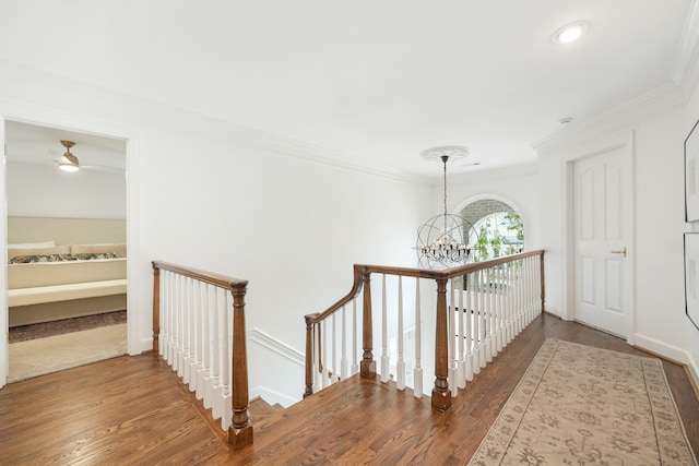 hallway with dark wood-type flooring, crown molding, and an inviting chandelier