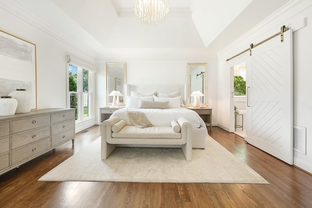 bedroom featuring dark hardwood / wood-style floors, ornamental molding, vaulted ceiling, a tray ceiling, and a barn door