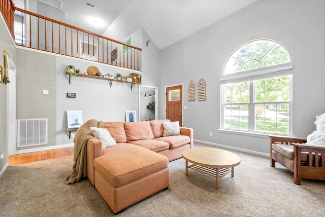 carpeted living room with high vaulted ceiling and plenty of natural light