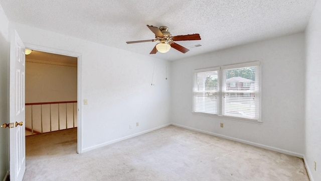 empty room featuring light carpet, ceiling fan, and a textured ceiling