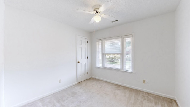 unfurnished room with ceiling fan, a textured ceiling, and light carpet