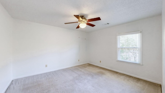 spare room with light carpet, ceiling fan, and a textured ceiling