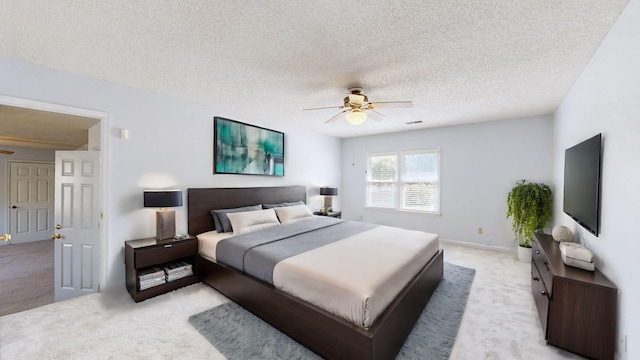 bedroom with ceiling fan, light carpet, and a textured ceiling