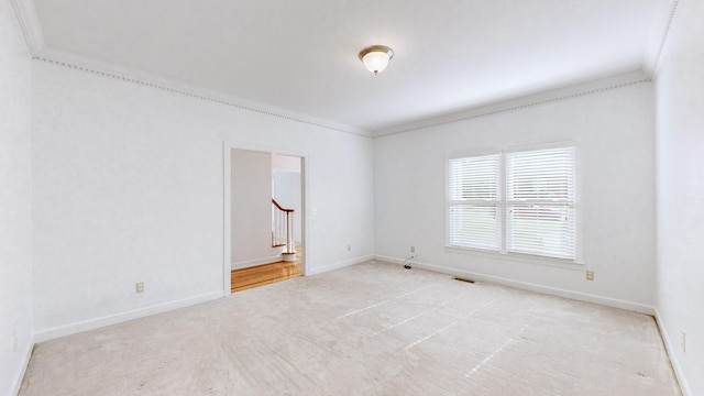 empty room with crown molding and light colored carpet