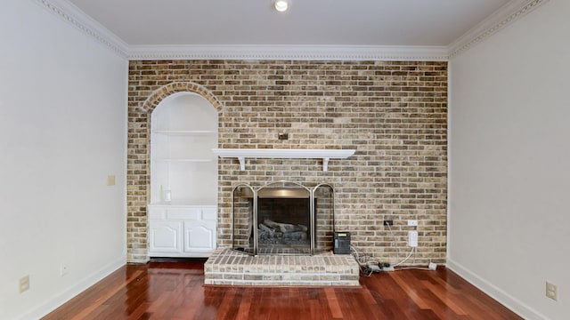 unfurnished living room featuring dark hardwood / wood-style floors, brick wall, crown molding, and a brick fireplace