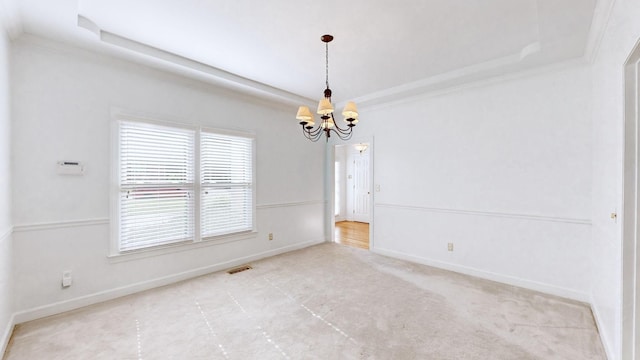 spare room with crown molding, a raised ceiling, and an inviting chandelier