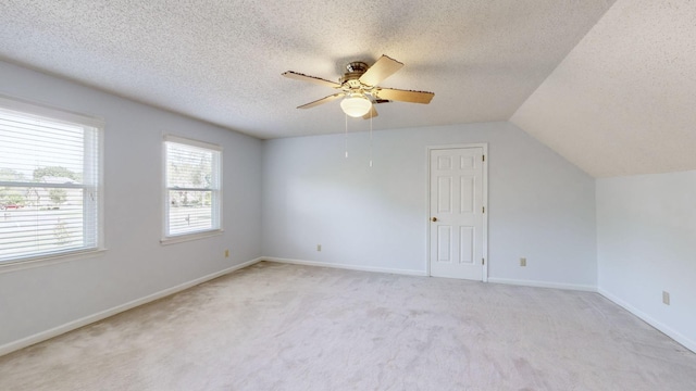 additional living space featuring ceiling fan, light colored carpet, a textured ceiling, and vaulted ceiling