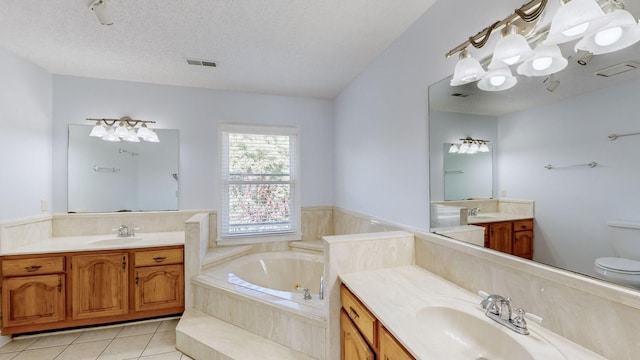 bathroom featuring tiled bath, vanity, tile patterned flooring, and a textured ceiling