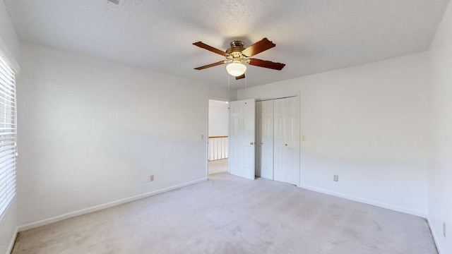 unfurnished bedroom featuring a textured ceiling, ceiling fan, a closet, and light colored carpet