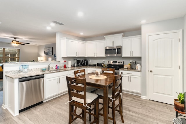 kitchen featuring kitchen peninsula, ceiling fan, stainless steel appliances, light hardwood / wood-style flooring, and sink