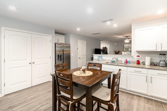 dining area with ceiling fan, light hardwood / wood-style flooring, and sink