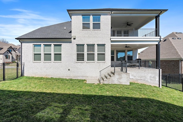 rear view of house featuring a ceiling fan, brick siding, a lawn, and a balcony