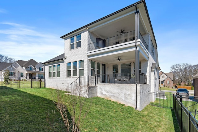 back of property featuring ceiling fan, a fenced backyard, a balcony, brick siding, and a yard