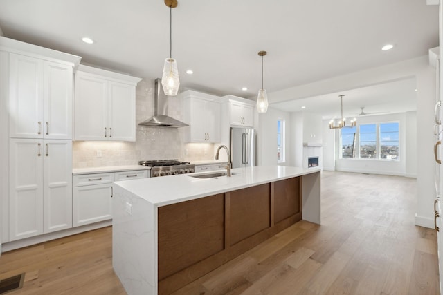 kitchen featuring pendant lighting, sink, white cabinetry, and wall chimney exhaust hood