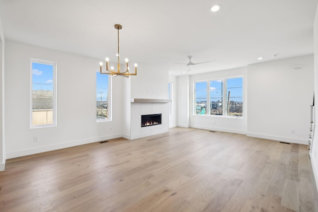 unfurnished living room featuring light wood-type flooring and ceiling fan with notable chandelier