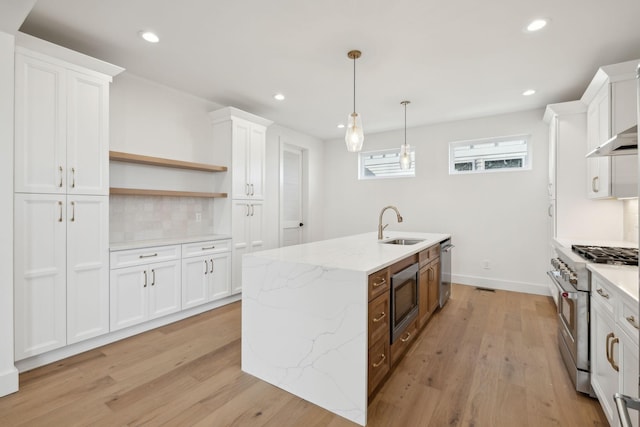 kitchen featuring light stone countertops, white cabinets, appliances with stainless steel finishes, sink, and hanging light fixtures